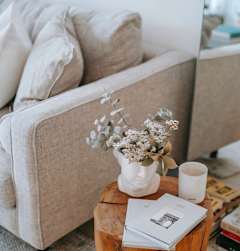 A wooden table with a vase of flowers and a book on it.