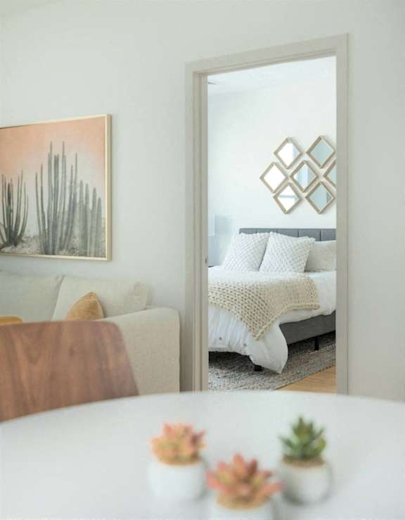 A white couch with a white blanket and pillows is reflected in a mirror.
