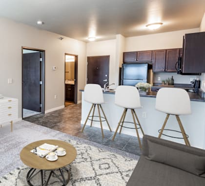 a kitchen and living room with a bar and stools in front of a counter