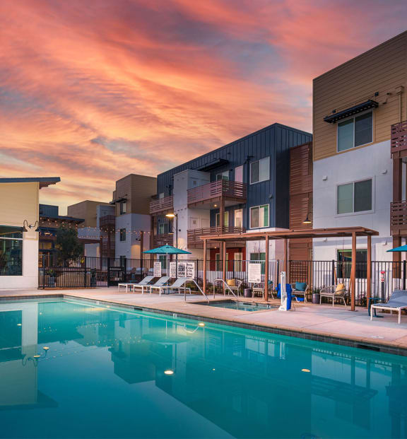 an apartment complex with a swimming pool at dusk