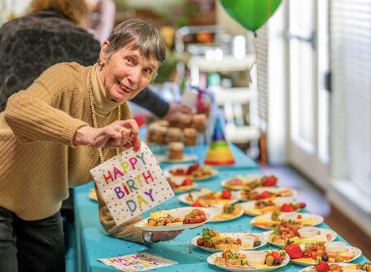 A woman is serving food at a birthday party.