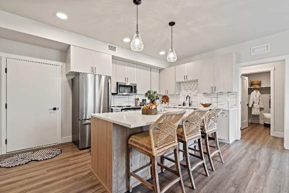 A kitchen with a white refrigerator and wooden chairs.