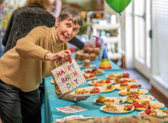 A woman is serving food at a birthday party.