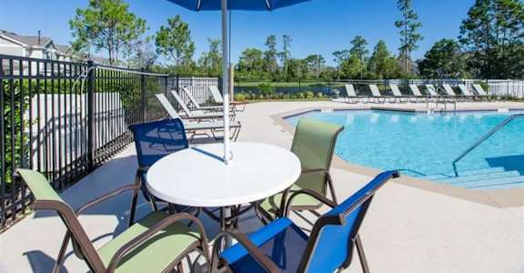 a table with a blue umbrella next to a pool