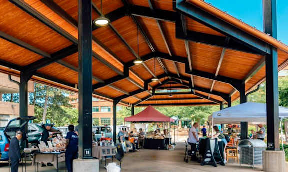 A marketplace with people shopping and stalls under a wooden roof.