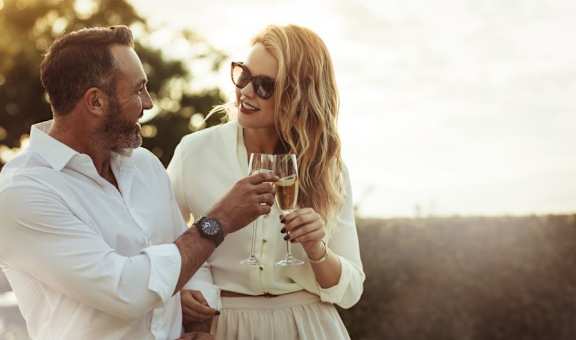 a man and woman holding wine glasses and looking at each other