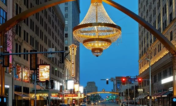 A street scene with a large chandelier hanging from the top of a streetlight.
