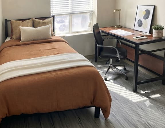 A bedroom with a bed, desk, and chair.