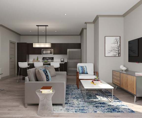 A living room at 49 West with a couch, TV on the wall, coffee table, and kitchen in the background. 