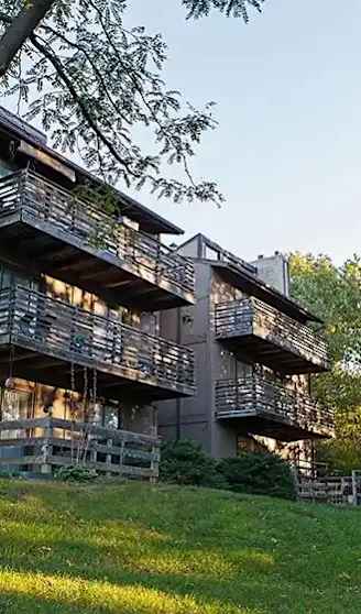 An apartment building with a green lawn and trees around it.
