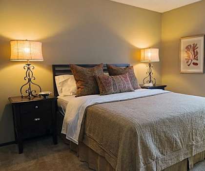 A bedroom with a bed, nightstands, and a window.