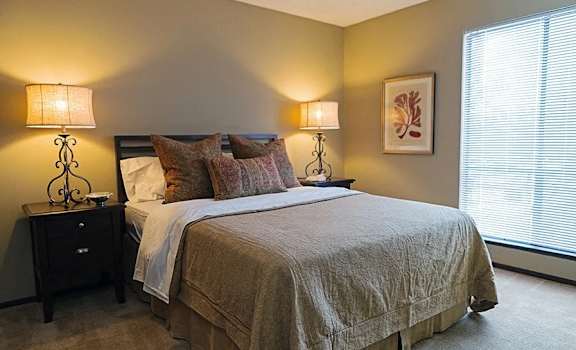 A bedroom with a bed, nightstands, and a window.