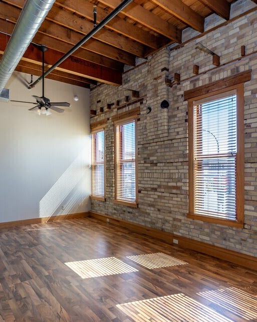 A room with wooden floors and a brick wall.