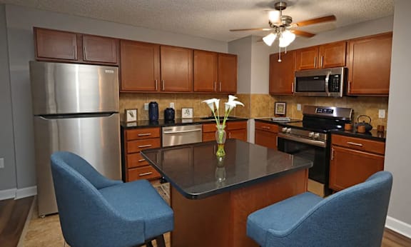 A kitchen with a black counter top and blue chairs.