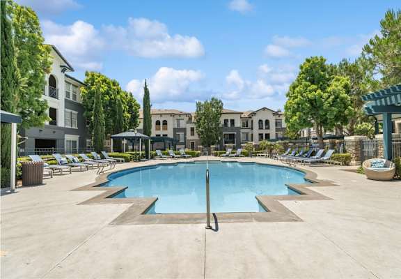 a swimming pool with chaise lounge chairs and trees in the background