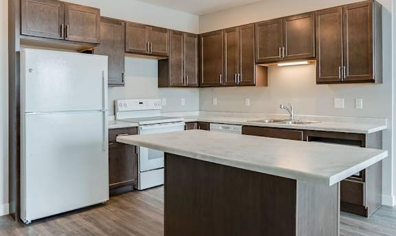 A kitchen with a white refrigerator and brown cabinets.