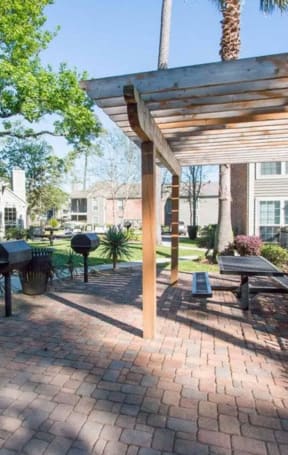 a patio with a wooden pergola and barbecue grill