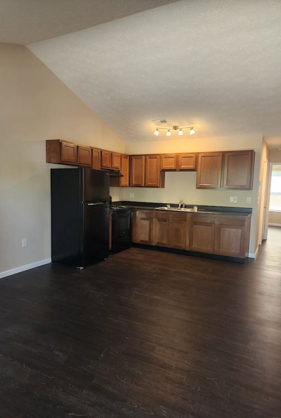 A kitchen with wooden cabinets and a black refrigerator.