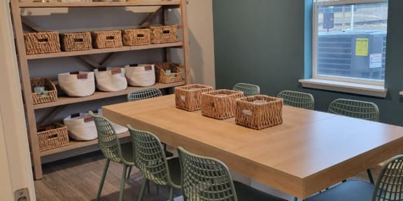 a dining room with a table and chairs and a shelf with baskets at southern meadows senior apartments in indianapolis