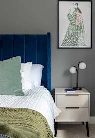 a bedroom with a bed and a nightstand with a lamp and a framed picture
