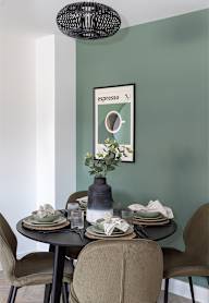 a dining room with a wooden table and blue chairs and a blue wall with artwork