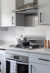 a modern kitchen with grey cabinets and black appliances at Leaf Living Nottingham