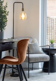a living room with a chair and a table with a lamp and a window at Leaf Living Nottingham