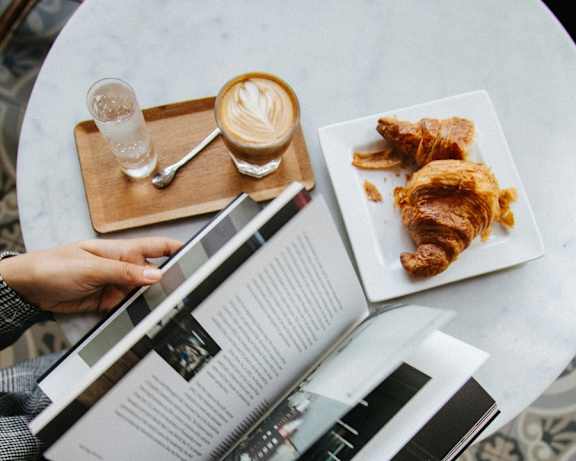 A person is reading a magazine while having a meal.