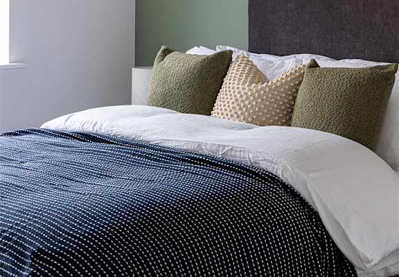 A bedroom with a bed and a framed picture on the wall.