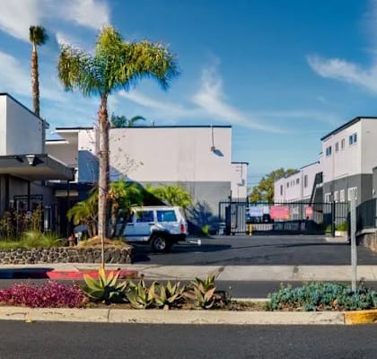 A street view of a residential area with houses and parked cars.