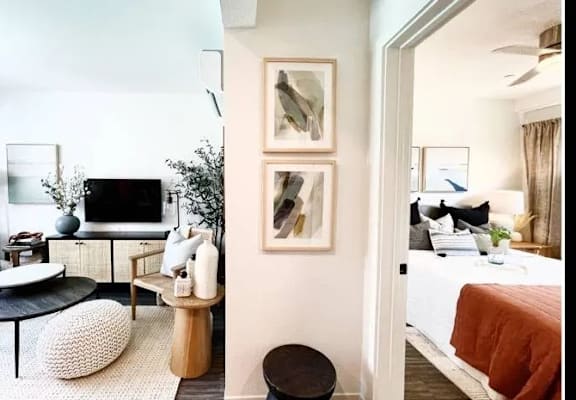 A modern living room with a black and white rug, a white sofa, a black coffee table, and a large painting on the wall.