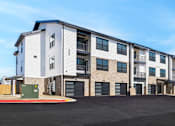 Thumbnail 14 of 27 - Apartment building with a parking lot in front.
