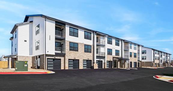 Apartment building with a parking lot in front.