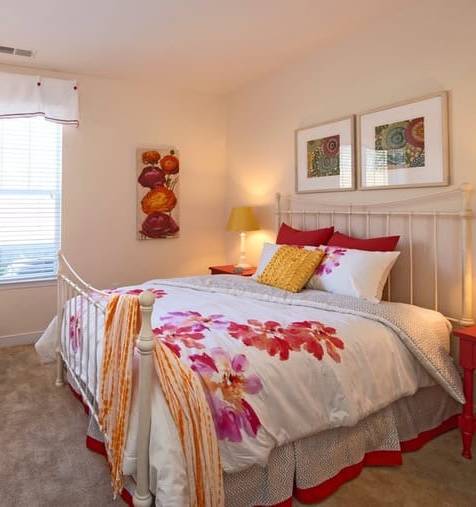 A bedroom with a bed, a chair, and a painting on the wall.