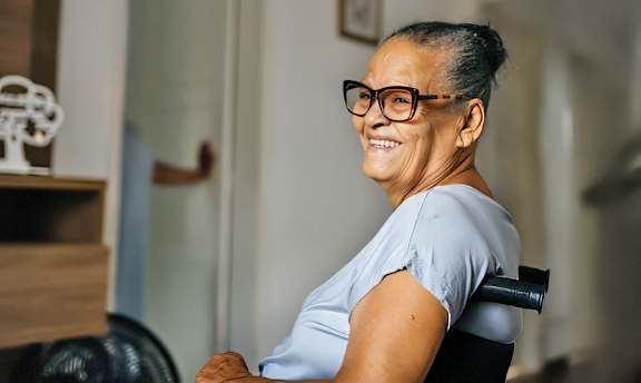 A woman in a grey shirt is sitting in a black wheelchair.