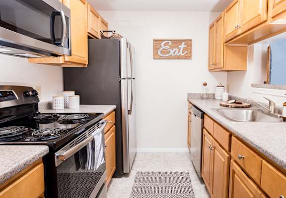 A kitchen with wooden cabinets and a black refrigerator.