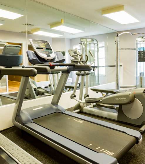 A treadmill and a stationary bike are in a gym.