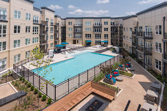 A large swimming pool surrounded by a black fence and a wooden deck.