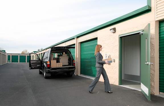 A woman in a business suit is walking towards a green storage unit.