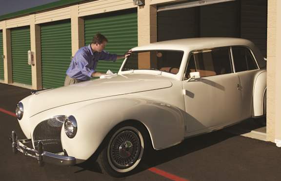 A man is working on a white vintage car.