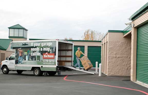 A truck with a man on the side is parked in front of a garage door.