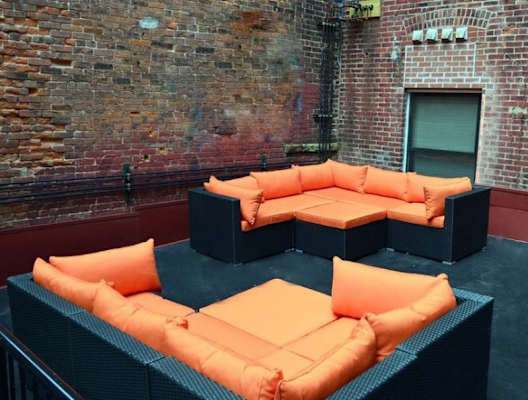 a group of couches on a patio in front of a brick wall