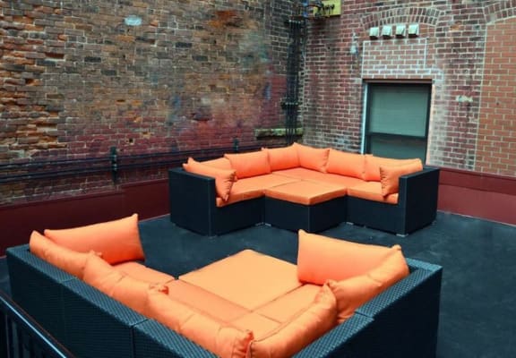 a group of couches on a patio in front of a brick wall
