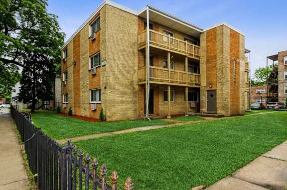 A brick apartment building with a green lawn in front.