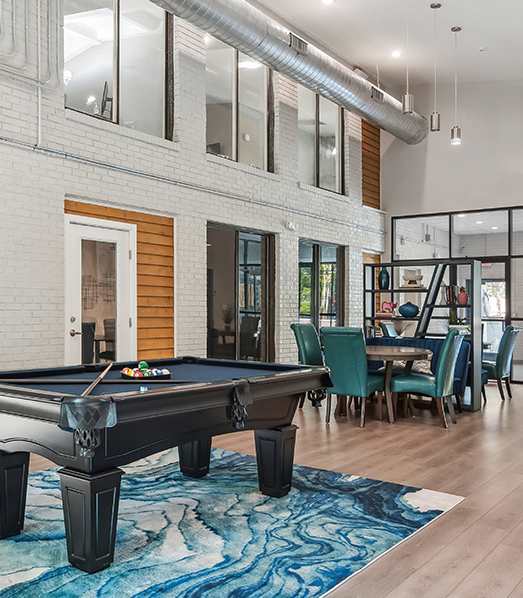 A pool table is in the middle of a room with a blue rug.