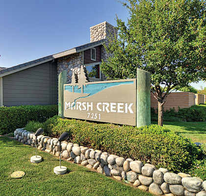 A sign that says Marsh Creek stands in front of a building.