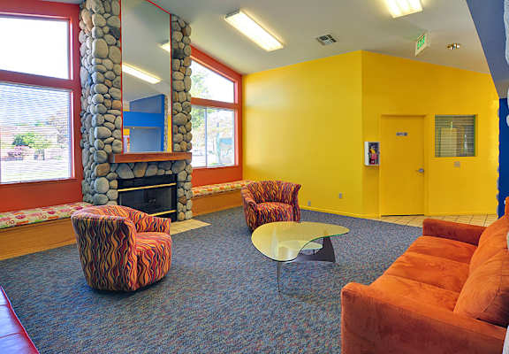 A yellow room with a stone fireplace and a red chair.