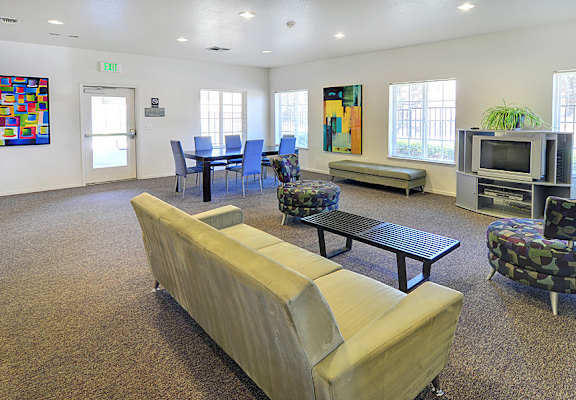A room with a couch, chairs, and a television set.