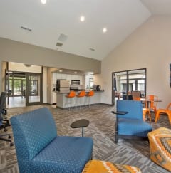 a clubhouse with blue chairs and a kitchen with a bar and a table