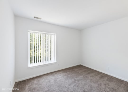 an empty room with a window and carpet